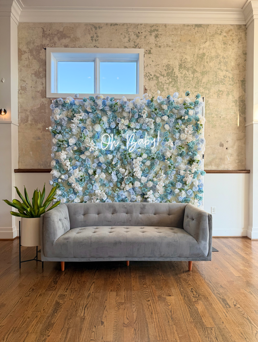 Straight-on view of an 8x8ft blue and white 3D silk flower wall with Oh Baby neon sign and lounge sofa setup for a baby shower backdrop.