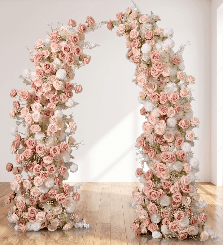 Floral archway made of pink and white roses on a wooden floor with a white wall background