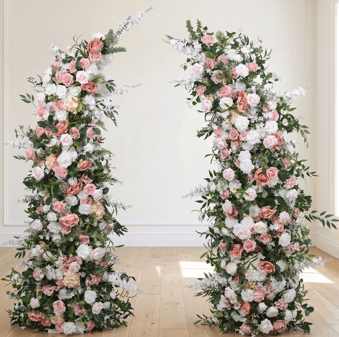 Two floral arches with pink, white, and green flowers on a wooden floor.