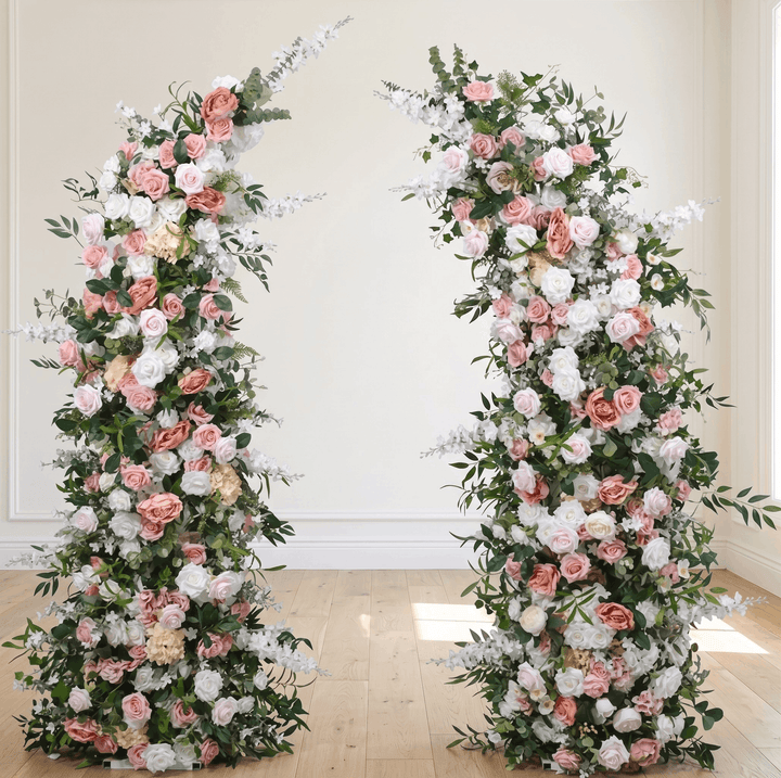 Two floral arches with pink, white, and green flowers on a wooden floor.
