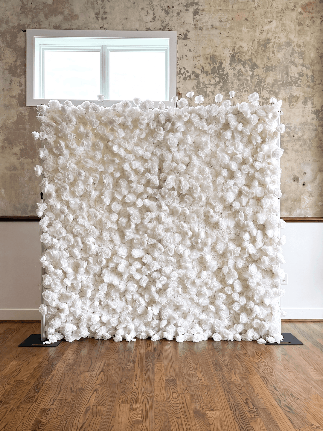 Detailed photograph of The Lilli white rose flower wall backdrop, showcasing the hand-crafted multi-dimensional pillow effect with varied bloom sizes for deep 3D texture on a durable white canvas backing.