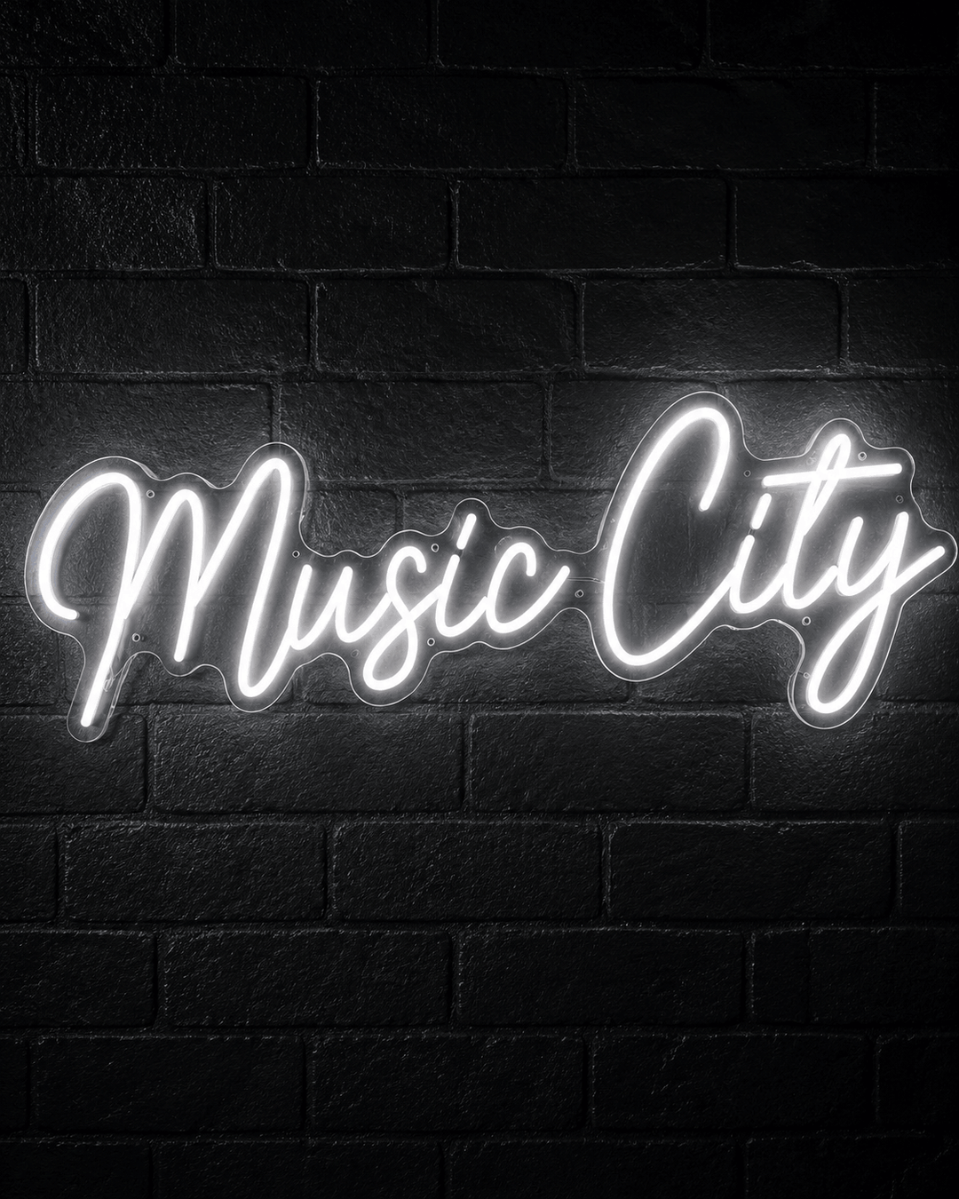 White Music City LED neon sign glowing on a black brick wall
