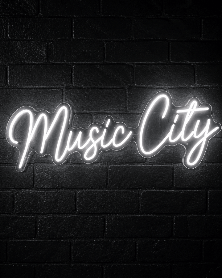 White Music City LED neon sign glowing on a black brick wall