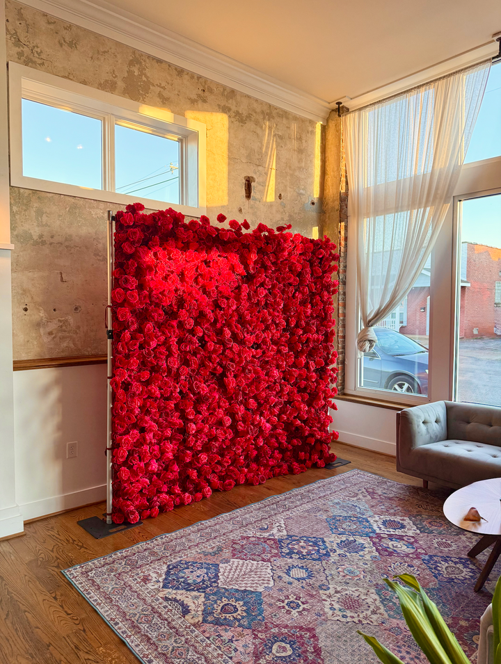 Side profile view of the Leigh red rose 3D silk flower wall mounted on a backdrop frame stand in natural light