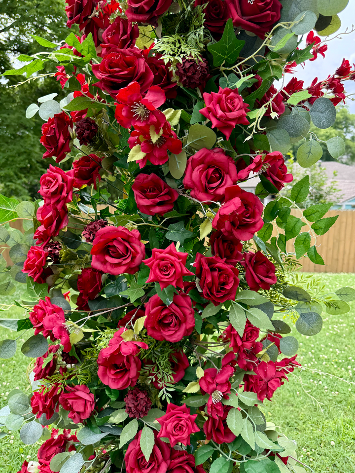 Bouquet of red roses with green leaves on a blurred natural background